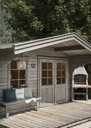 Kleine Holzhütte mit kleiner Holzbank und Grillofen