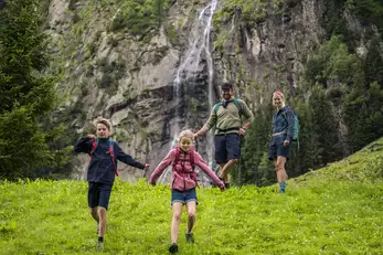 Familie mit zwei kleinen Kindern am Wandern im Stilluptal mit Wasserfall