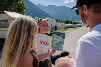 Erwachsene Menschen schauen sich am Campingplatz den Lageplan an