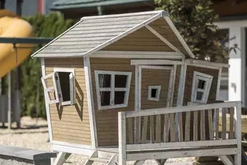 kleine Holzhütte für Kinder am Spielplatz mit Fenstern und Türen