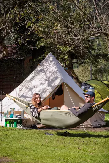 Zwei Erwachsene Menschen sitzen in einer Hängematte am Campingplatz
