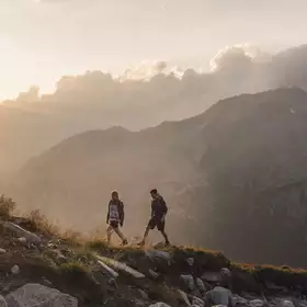 Zwei Wanderer gehen bei Sonnenuntergang auf den Berg
