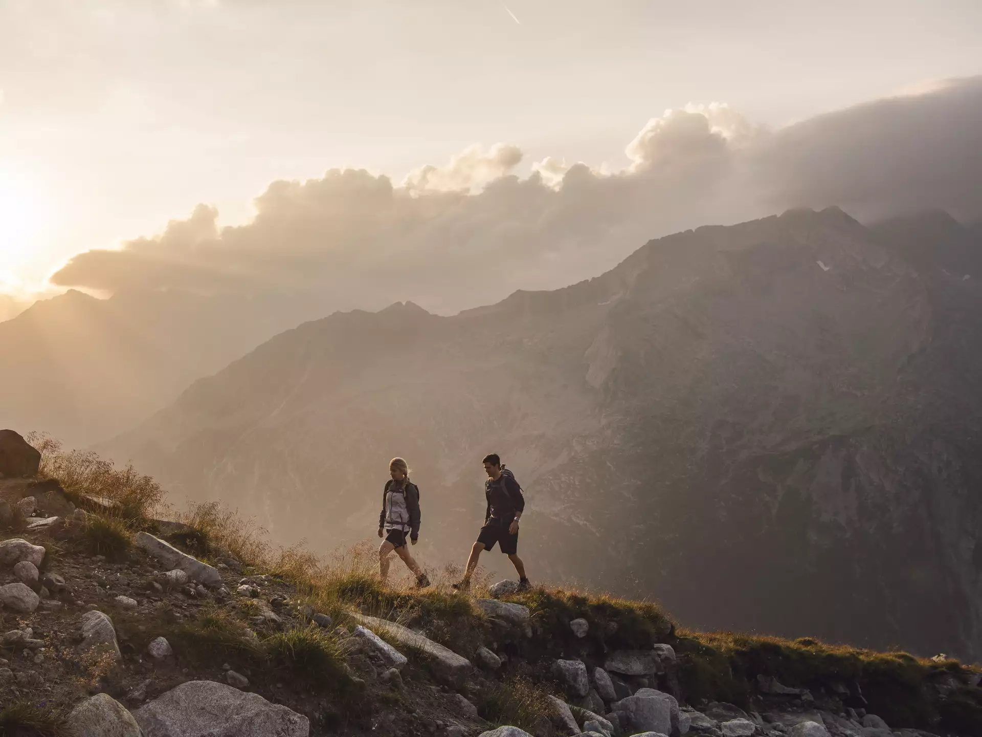 Zwei Wanderer gehen bei Sonnenuntergang auf den Berg