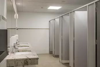 Drei kleinere Waschbecken mit WC Kabinen im Sanitärraum