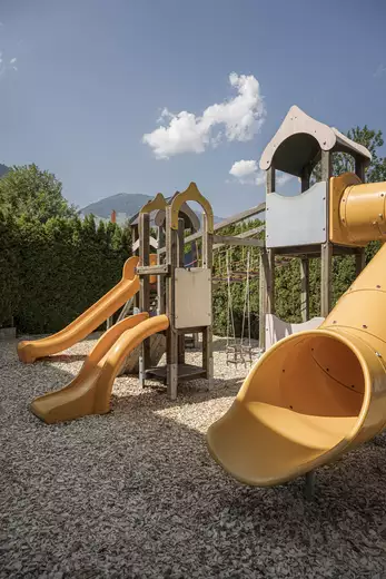 Foto von drei verschiedenen gelben Rutschen mit Klettergerüst am Spielplatz