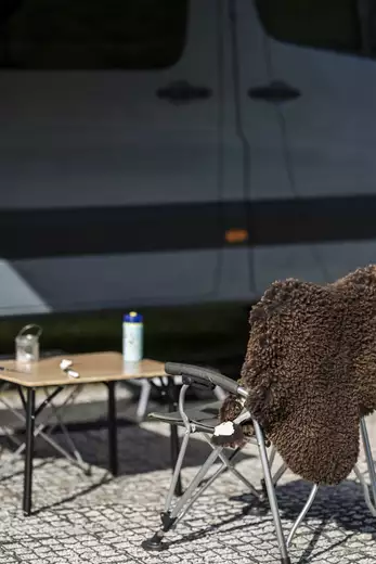 Campingstuhl mit kleinem Campingtisch vor einem Camper