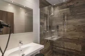 Sanitärbereich mit Föhn, großem Waschbecken und moderner Dusche