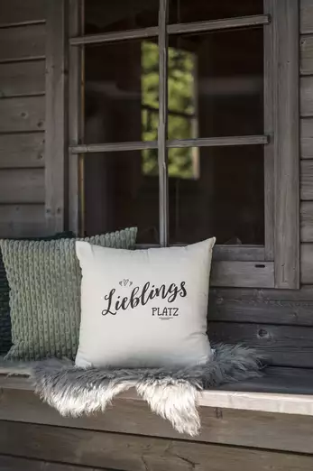 Detailaufnahme Holzbank mit zwei Polstern vor einer Holzhütte