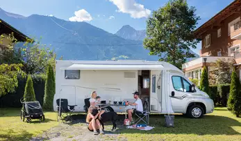 Wohnwagen mit Campingtisch und Campingstühlen