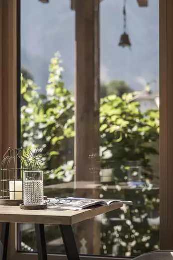 Holztisch mit Tischdeko, Wasserglas und kleiner Zeitung