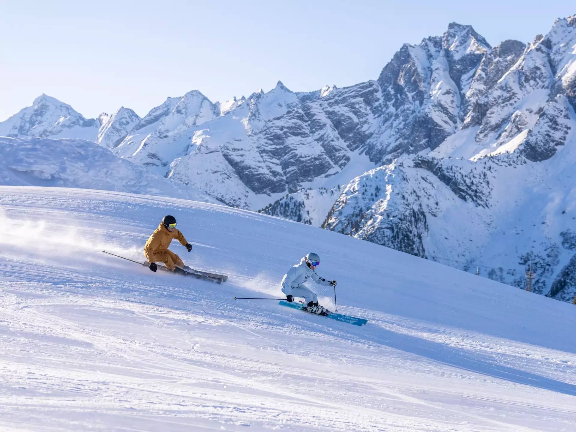Zwei Skifahrer fahren auf präparierter Piste mit Bergpanorama